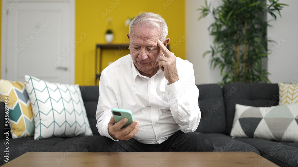 Fototapeta premium senior using smartphone with serious expression at home