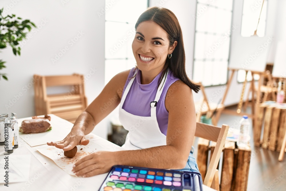 Young beautiful hispanic woman artist smiling confident touching clay at art studio Young beautiful hispanic woman artist smiling confident touching clay at art studio
