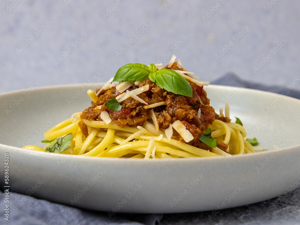 vegan bolognese made from seitan and kamut with vegan spaghetti and vegan parmesan, garnished