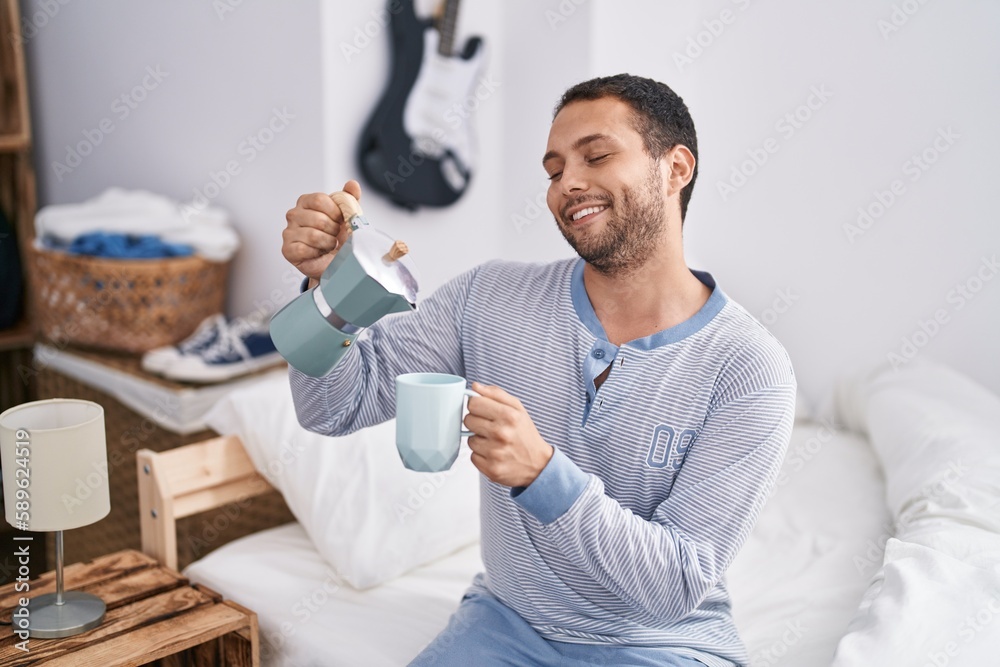Young man drinking cup of coffee sitting on bed at bedroom Young man drinking cup of coffee sitting on bed at bedroom