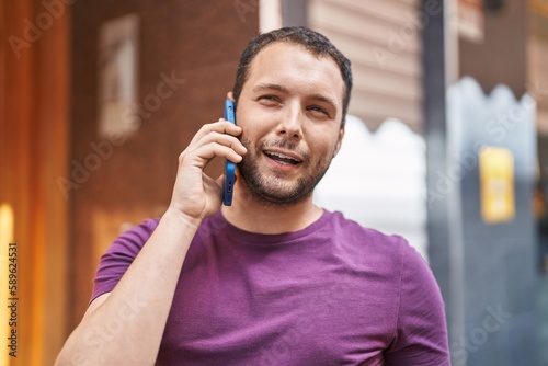 Young man smiling confident talking on the smartphone at street