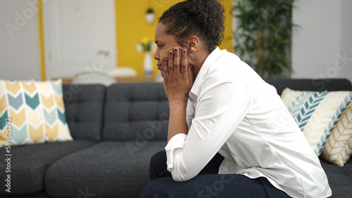 African american woman sitting on sofa with stressed expression at home