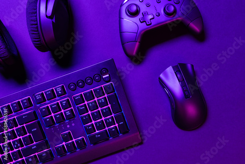 Top view of illuminated gaming gadgets on purple desk