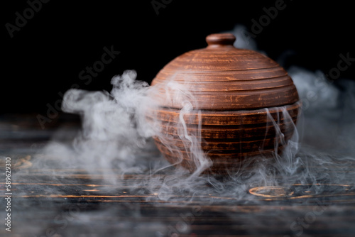 smoke from dry ice in a brown dish with a lid on a dark background