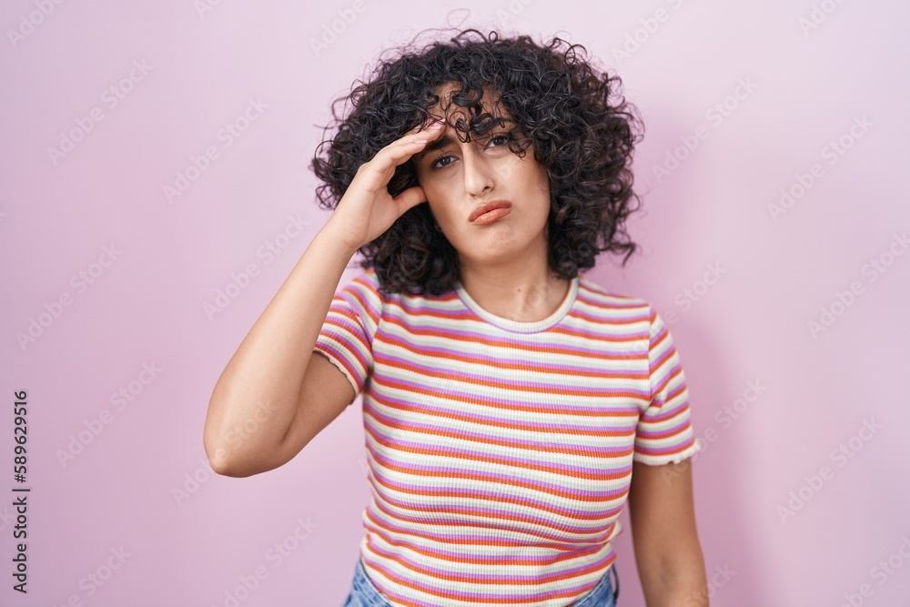Young middle east woman standing over pink background worried and stressed about a problem with hand on forehead, nervous and anxious for crisis Young middle east woman standing over pink background worried and stressed about a problem with hand on forehead, nervous and anxious for crisis