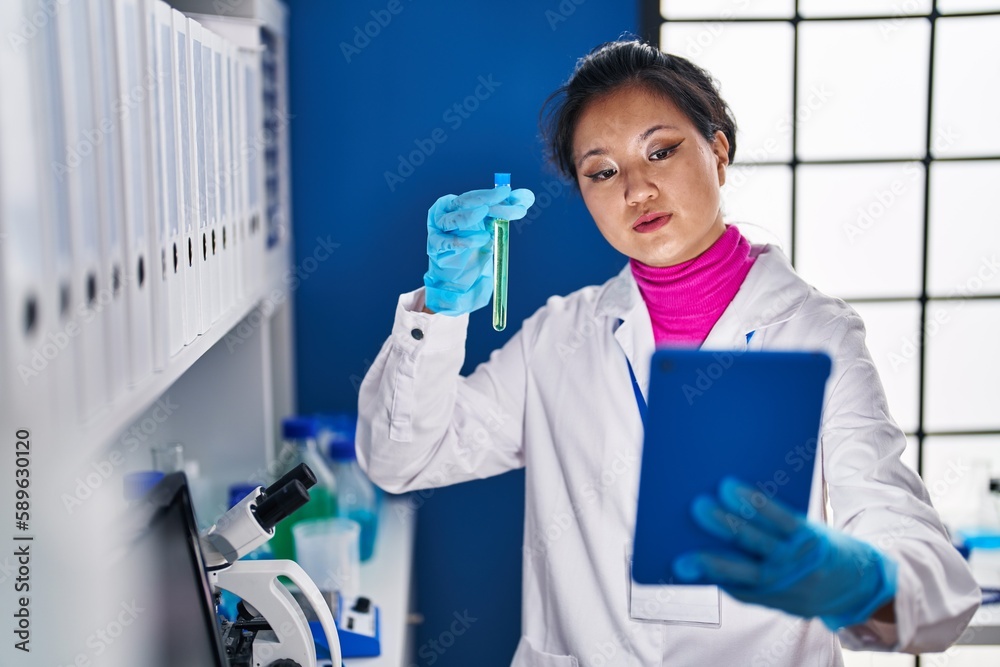 Young chinese woman scientist holding test tube having video call at laboratory Young chinese woman scientist holding test tube having video call at laboratory