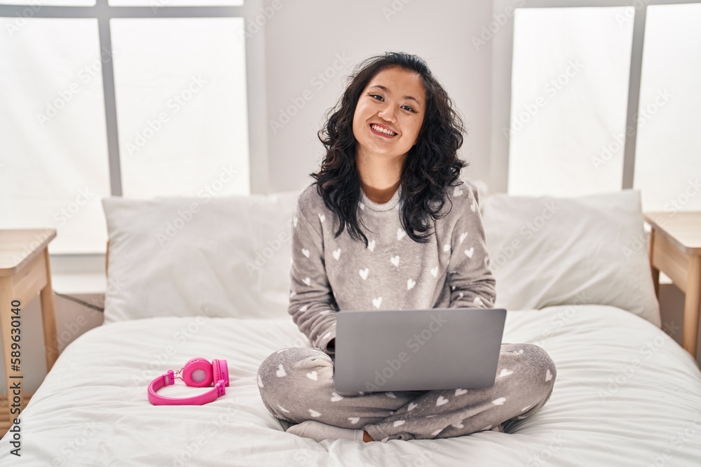 Young chinese woman using laptop sitting on bed at bedroom Young chinese woman using laptop sitting on bed at bedroom