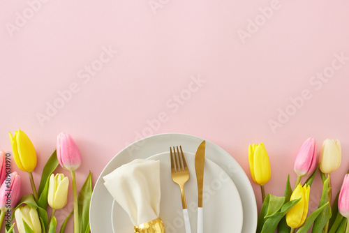 Mother's Day celebration concept. Top view photo of circle plate cutlery knife fork fabric napkin with ring yellow pink tulips on isolated pastel pink background with empty space