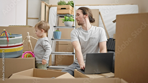 Father and son unpacking cardboard box using laptop at new home © Krakenimages.com