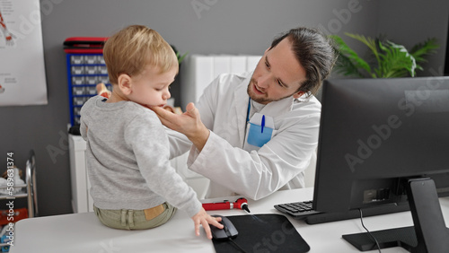 Father and son doctor examining throat at clinic