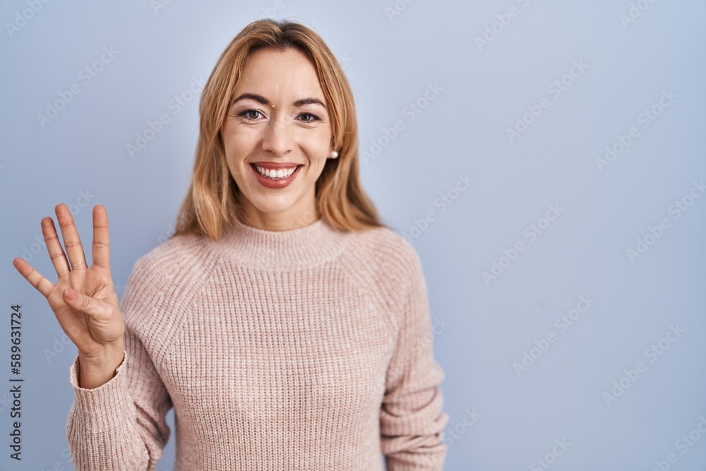 Hispanic woman standing over blue background showing and pointing up with fingers number four while smiling confident and happy. Hispanic woman standing over blue background showing and pointing up with fingers number four while smiling confident and happy.