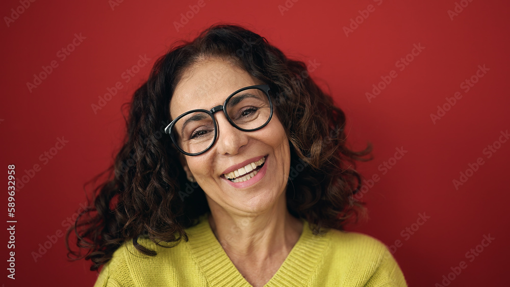 Obraz premium Middle age hispanic woman smiling confident standing over isolated red background