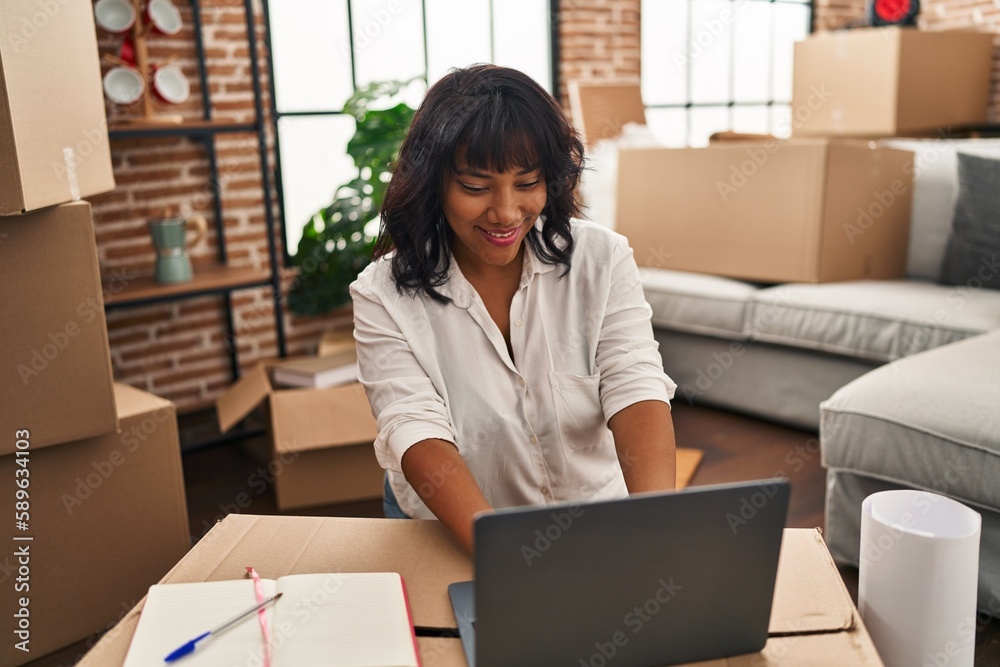 Young beautiful latin woman using laptop sitting on floor at new home Young beautiful latin woman using laptop sitting on floor at new home