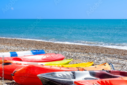 Canoes on the beach, kayaks on the seashore, water sports, plastic boats for tourists on a pebble beach