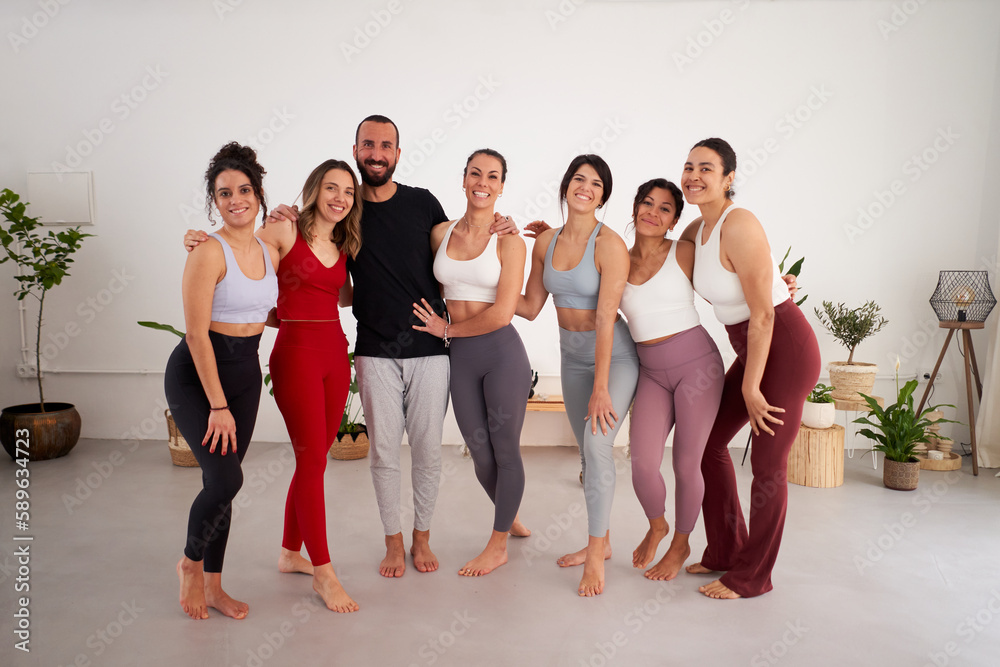 Fototapeta premium Cheerful group of yoga class colleagues embracing each other standing front of camera looking at it happy.