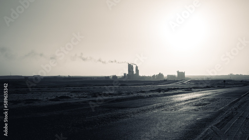 silhouette of the cement factory in the middle of the desert and the smoke rising high and stretching long away from it