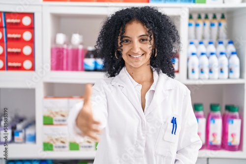 Young hispanic woman pharmacist smiling confident shake hands at pharmacy