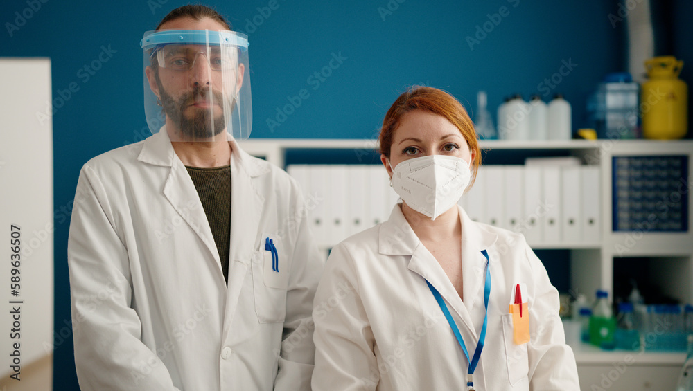 Man and woman wearing sciencist uniform standing with arms crossed gesture at laboratory Man and woman wearing sciencist uniform standing with arms crossed gesture at laboratory