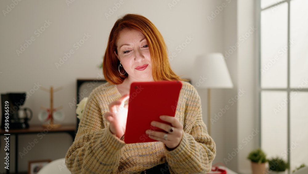 Young redhead woman using touchpad standing at home Young redhead woman using touchpad standing at home
