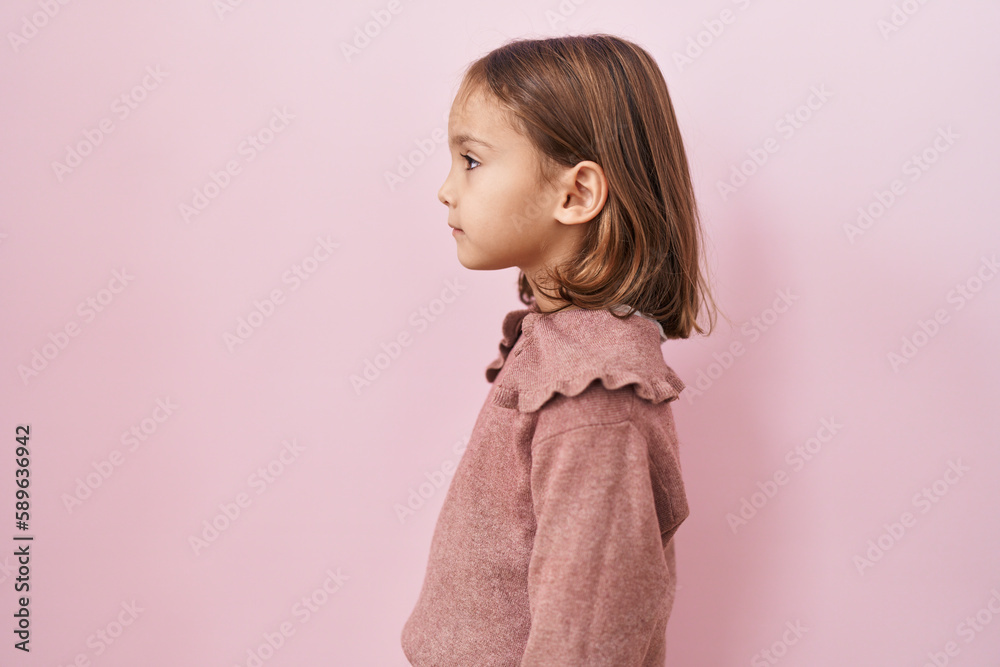 Little hispanic girl standing over pink background looking to side, relax profile pose with natural face with confident smile. Little hispanic girl standing over pink background looking to side, relax profile pose with natural face with confident smile.