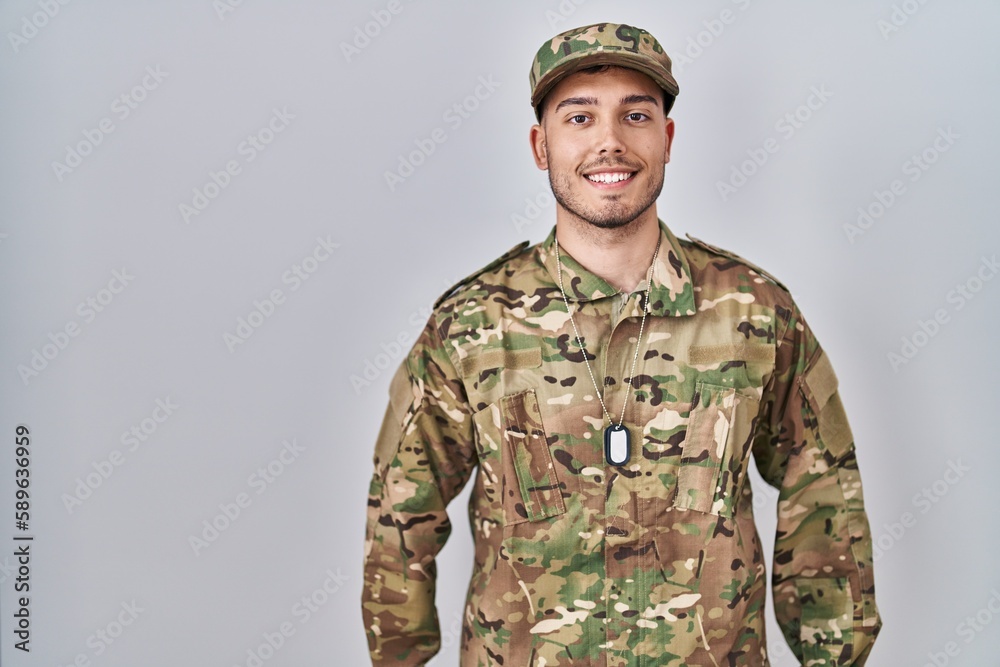 Young hispanic man wearing camouflage army uniform with a happy and cool smile on face. lucky person. Young hispanic man wearing camouflage army uniform with a happy and cool smile on face. lucky person.