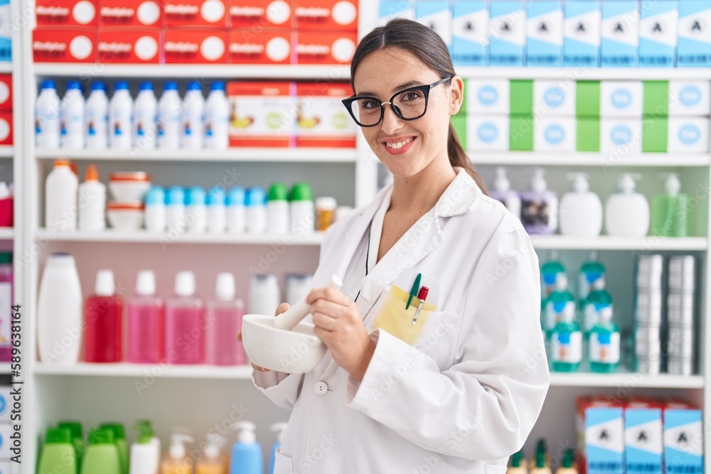 Young beautiful hispanic woman pharmacist smiling confident make mixture at pharmacy