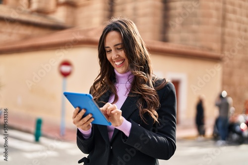 Young hispanic woman smiling confident using touchpad at street