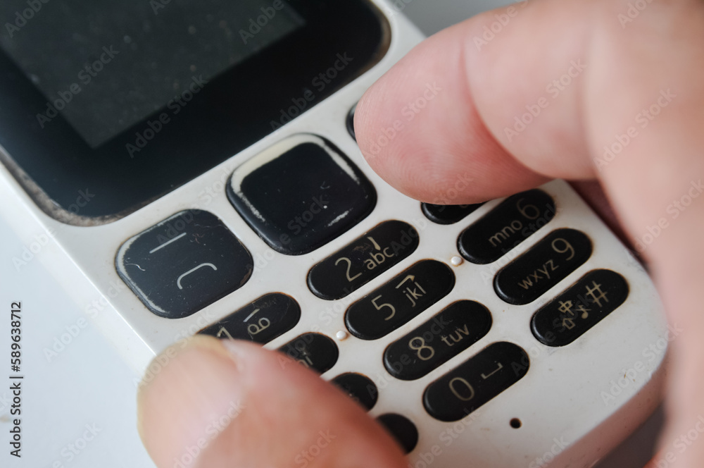 fingers or hands of someone who is holding an old GSM mobile phone on the keypad fingers or hands of someone who is holding an old GSM mobile phone on the keypad