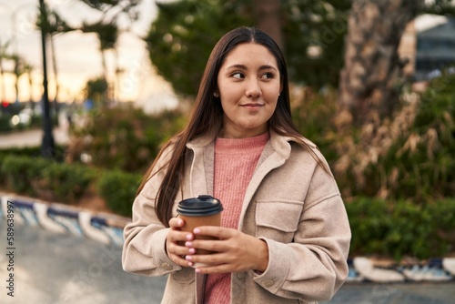Young hispanic woman smiling confident drinking coffee at park