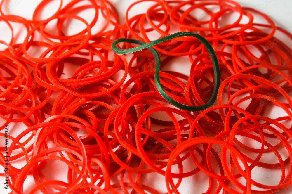 green rubber band in a pile or collection of other red rubber bands can be used as a background