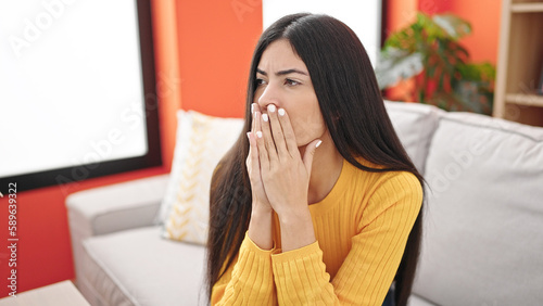 Young beautiful hispanic woman stressed sitting on sofa at home