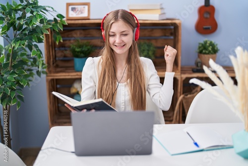 Young caucasian woman studying using computer laptop screaming proud, celebrating victory and success very excited with raised arm