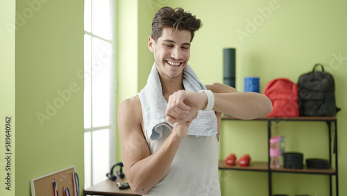 Young hispanic man smiling confident using stopwatch at sport center