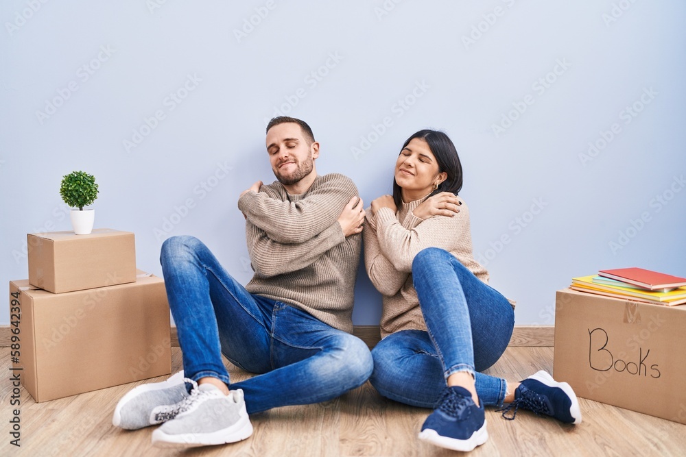 Young couple moving to a new home hugging oneself happy and positive, smiling confident. self love and self care Young couple moving to a new home hugging oneself happy and positive, smiling confident. self love and self care