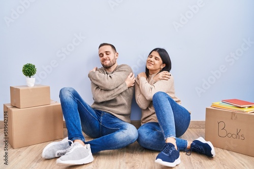 Young couple moving to a new home hugging oneself happy and positive, smiling confident. self love and self care © Krakenimages.com