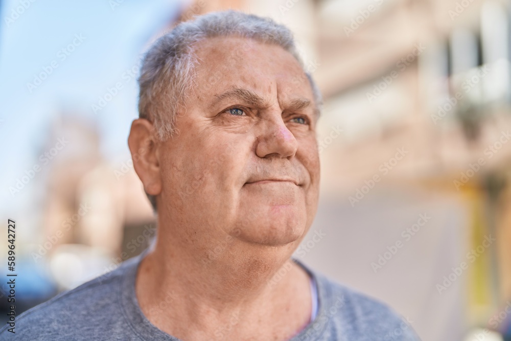 Middle age grey-haired man looking to the side with relaxed expression at street