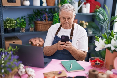 Middle age grey-haired man florist using smartphone at florist