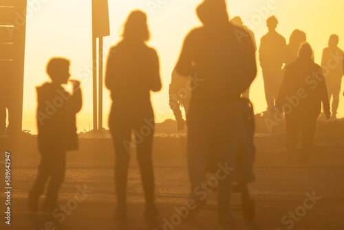 Silhouettes of people in the light of a bright orange sunset