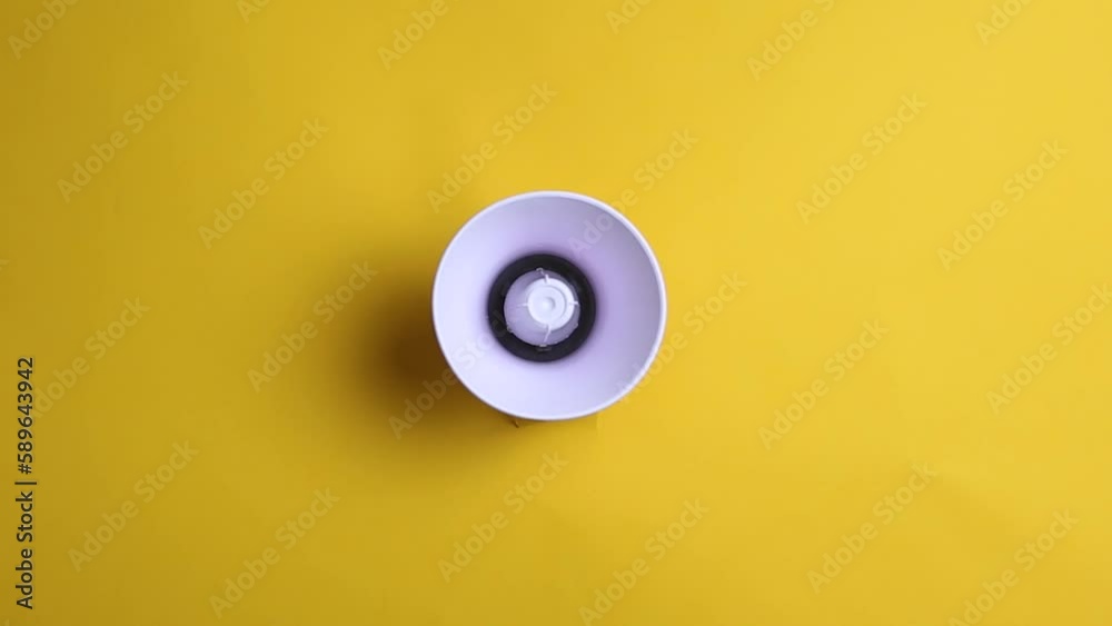 Megaphone peeking out of a hole on a yellow background. Megaphone peeking out of a hole on a yellow background.