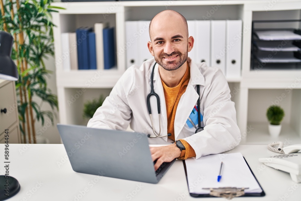 Young man wearing doctor uniform using laptop at clinic Young man wearing doctor uniform using laptop at clinic