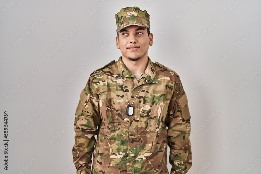 Young arab man wearing camouflage army uniform smiling looking to the side and staring away thinking. Young arab man wearing camouflage army uniform smiling looking to the side and staring away thinking.
