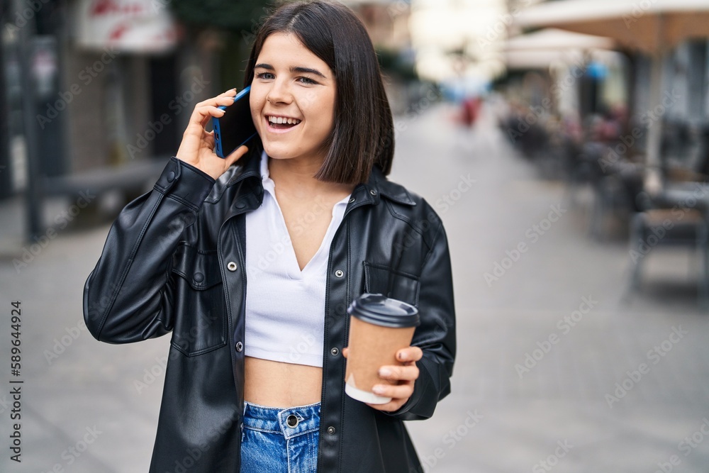 Fototapeta premium Young beautiful hispanic woman talking on the smartphone drinking coffee at street