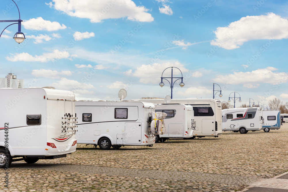 Many white modern campervan recreational motor home vehicles parked in