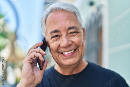 Middle age grey-haired man smiling confident talking on the smartphone at street