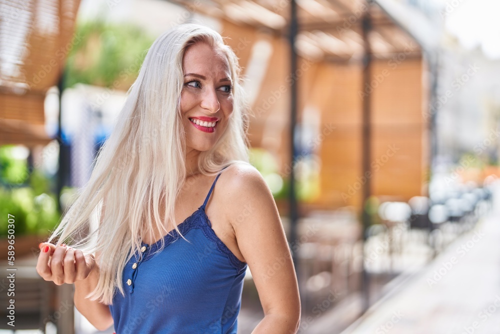 Young blonde woman smiling confident looking to the side at street Young blonde woman smiling confident looking to the side at street