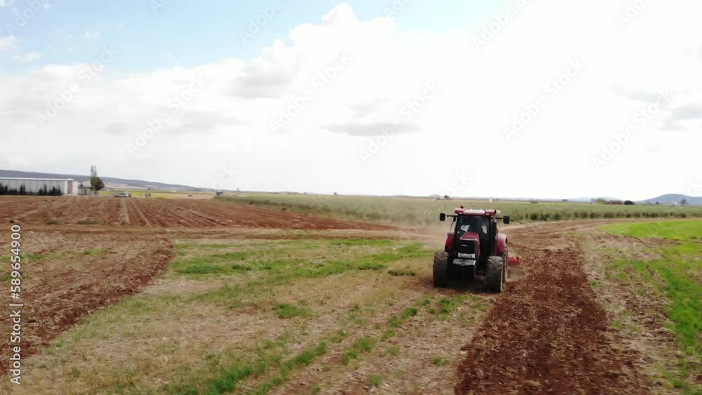 Red tractor working on the field in Spain making tillage Red tractor working on the field in Spain making tillage