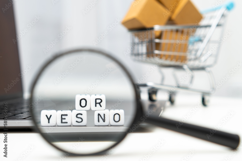A magnifying glass is used to view cubes with words Yes or No, while a toy shopping cart and boxes serve as the background. 