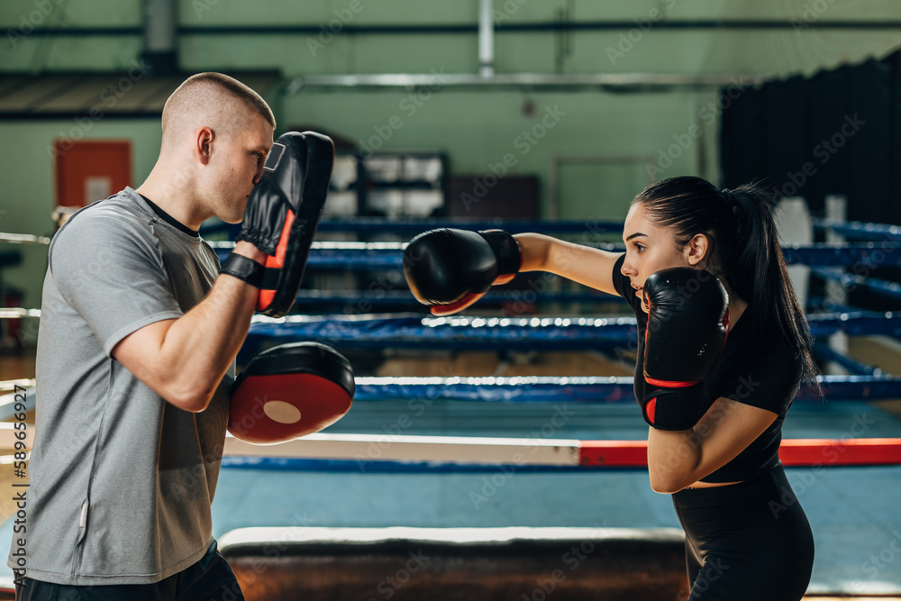 Side view of a woman practicing her punch with a trainer