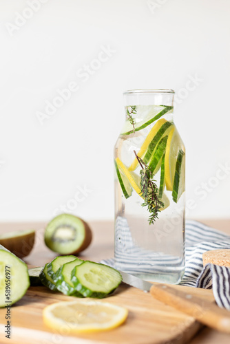 Infused  water with cucumber, lemon and thyme in glass bottle on wooden table. Diet, detox, healthy eating, weight loss concept