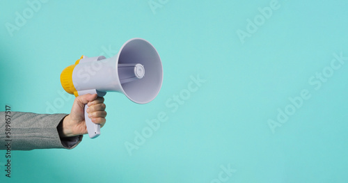 Hand is hold megaphone and wear grey suit on mint green or Tiffany Blue background..